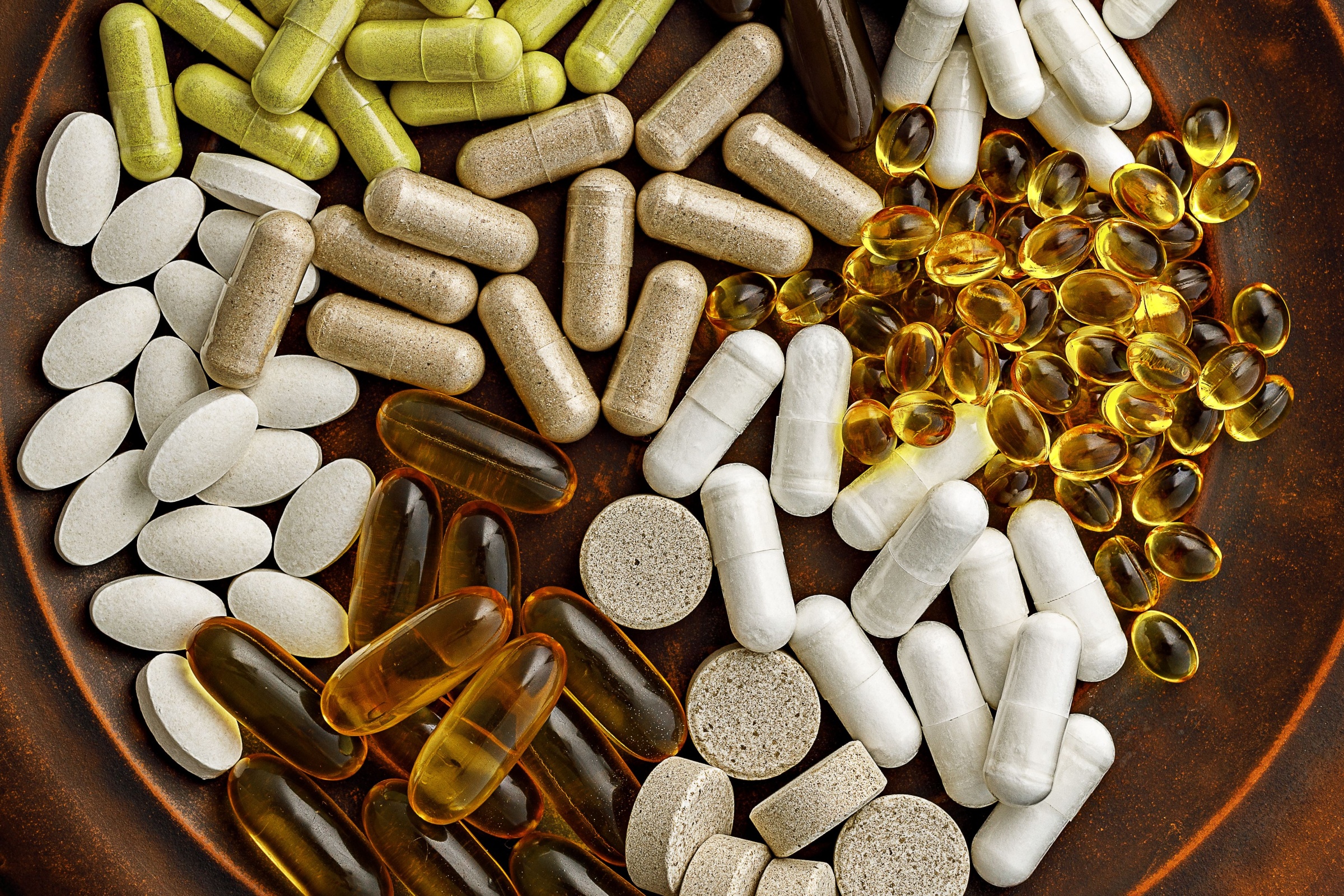 multivitamin dietary supplements on a clay plate. dietary supplements top view. mental wellbeing and personal health concept.