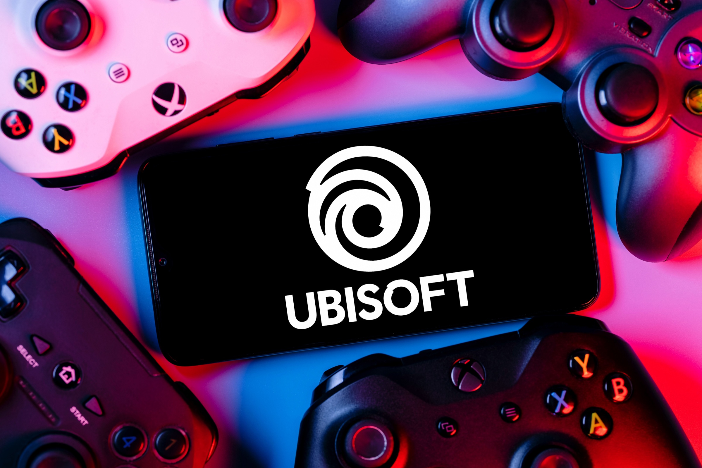 Kazan, Russia - Apr 15, 2022: Ubisoft is French video game company. Smartphone with Ubisoft logo on screen surrounded by gamepads.